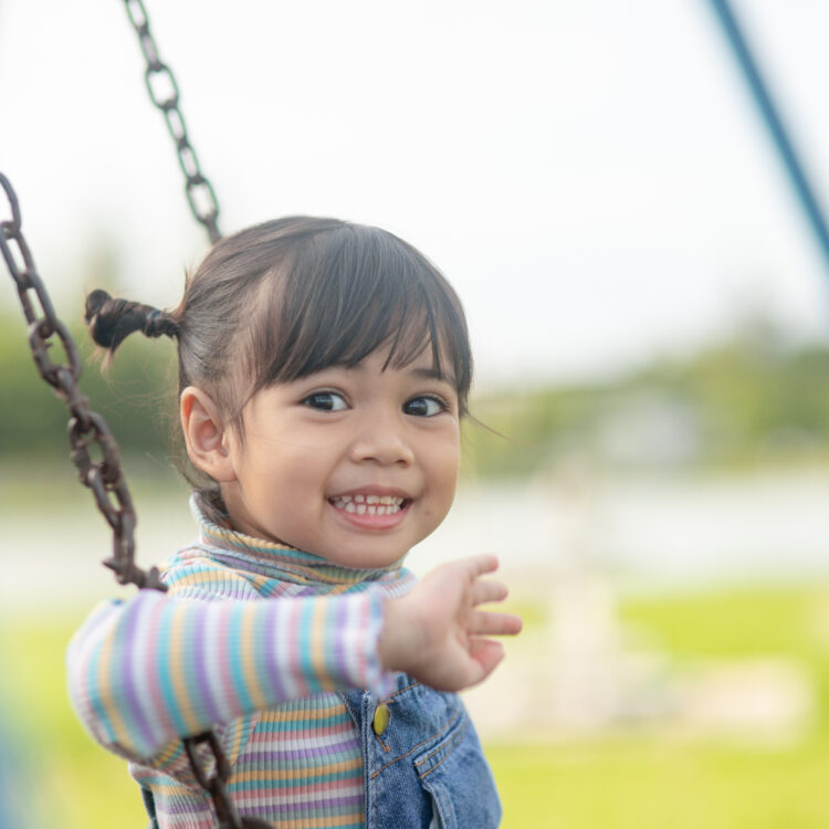 Girl smiling on a swing at the park, Tracy, CA