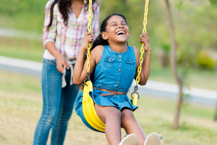 Mother and Daughter showing off daughter's smile on a swing in Tracy, CA