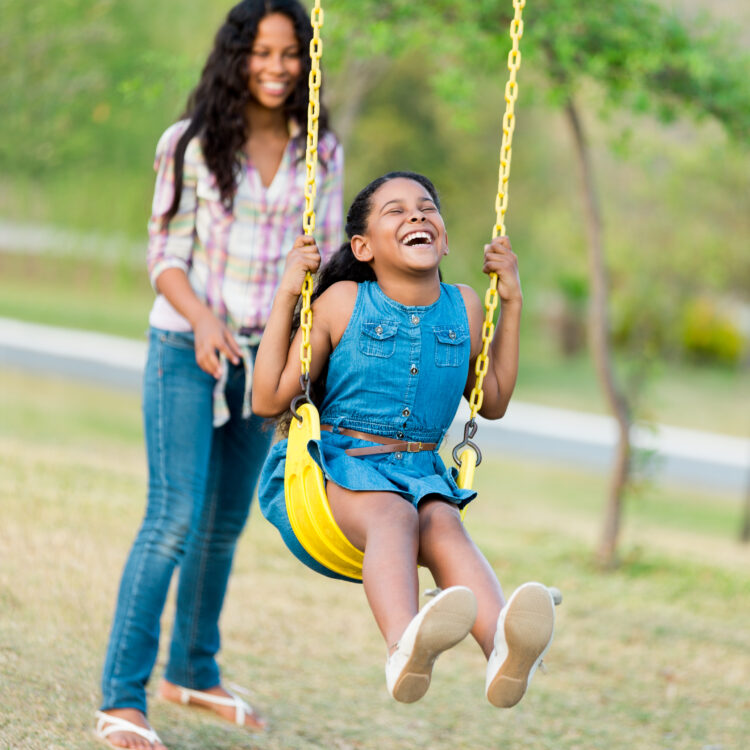 Mother and Daughter showing off daughter's smile on a swing in Tracy, CA
